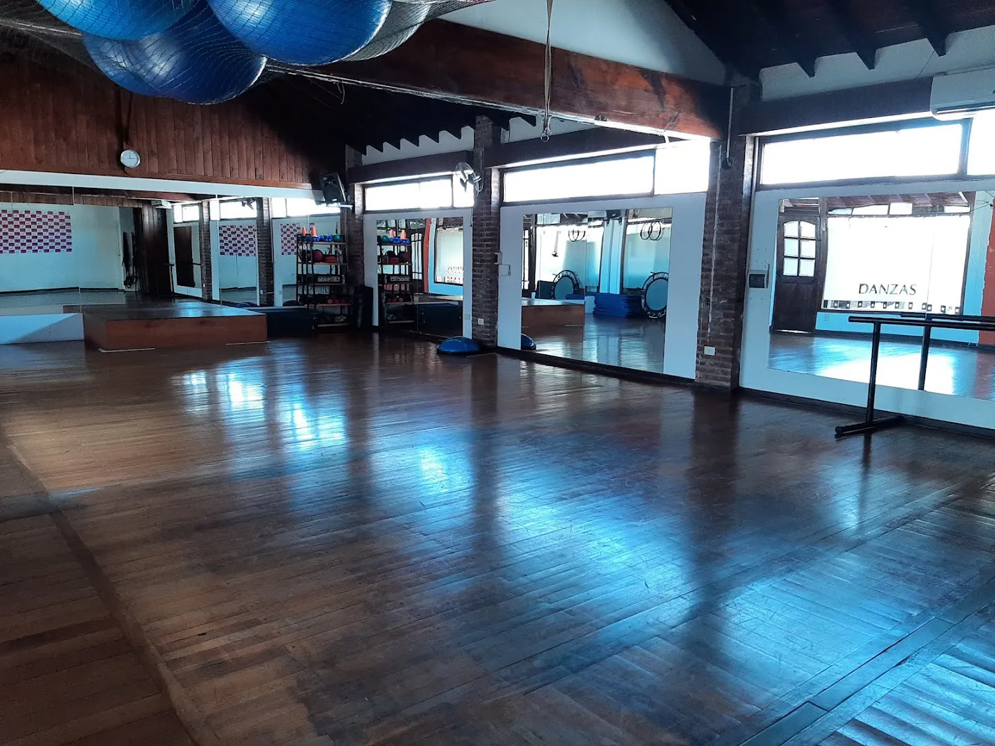 El salón de Fit con piso de madera, pelotas colgadas y espejos